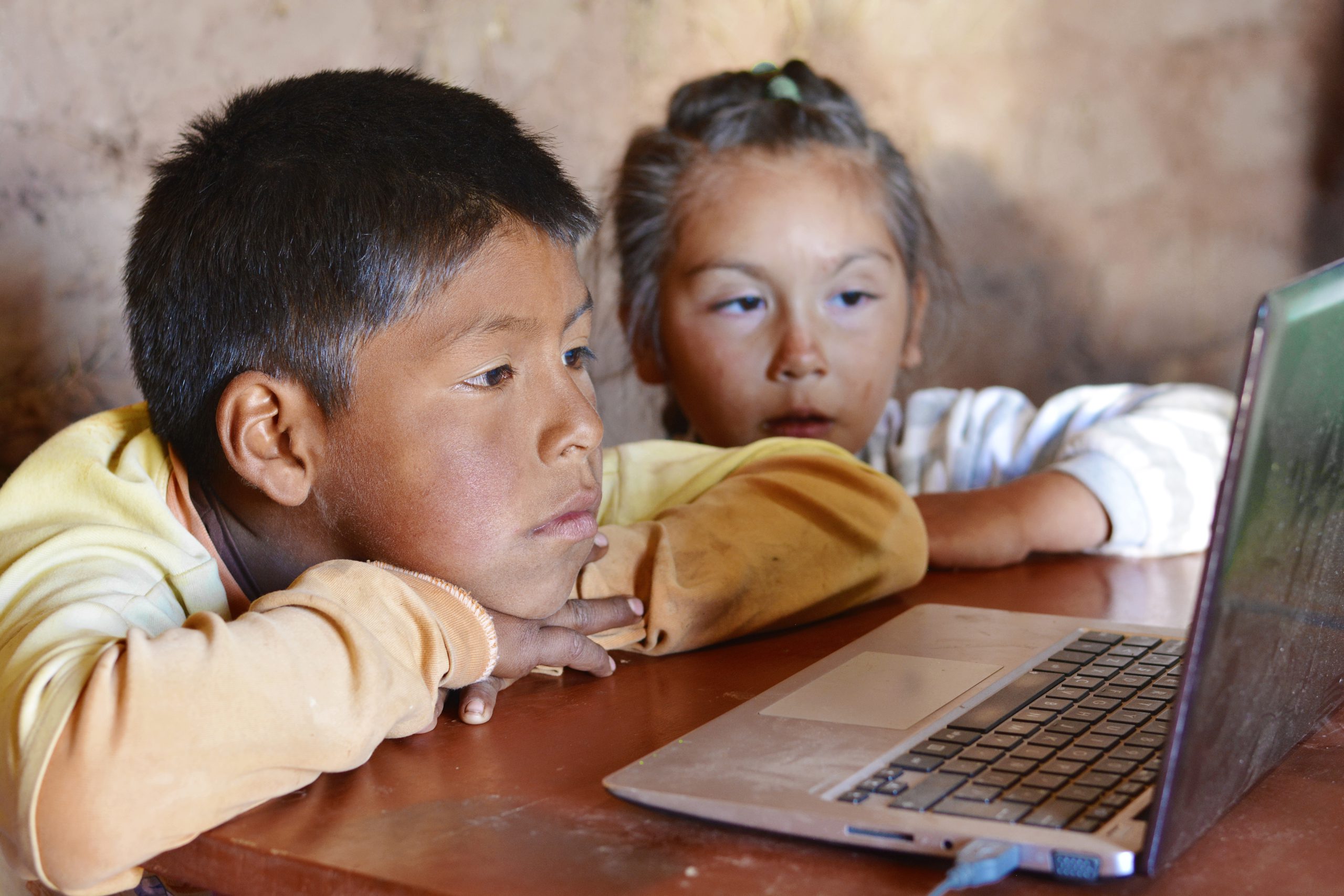 Crianças olham para tela do computador.